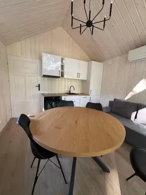 a living room with a wooden table and a kitchen at Domki nad Krzyworzeką in Dobczyce