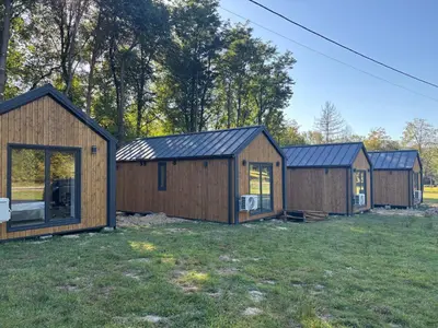 a row of wooden houses in a field at Domki nad Krzyworzeką in Dobczyce