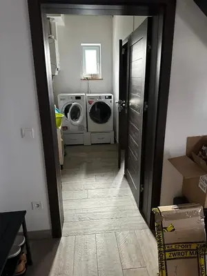a hallway leading to a laundry room with a washer and dryer at Domek na Krakowskiej in Kęty
