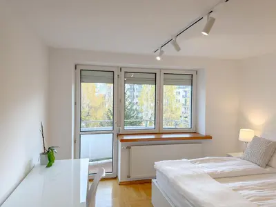 a bedroom with a bed and a table and windows at Fabryczna City Residence 100m2 Balcony by Gio Loft in Kraków