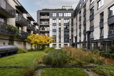 an apartment building with a garden in front of it at Kraków Wawrzyńca Suites by Downtown Apartments in Kraków
