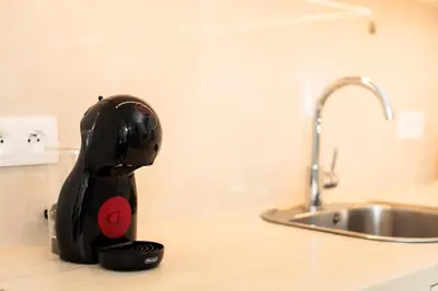 a black appliance sitting on a counter next to a sink at City of the Kings - Solaris Apartment in Kraków