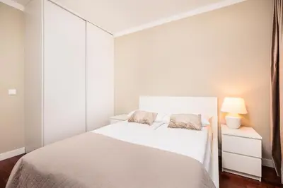 a white bedroom with a bed and a lamp at City of the Kings - Solaris Apartment in Kraków