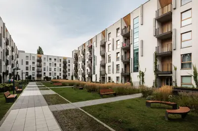 a row of apartment buildings with benches in a park at City of the Kings - Eden Apartment in Kraków