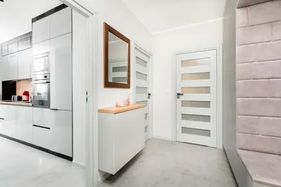 a kitchen with white cabinets and a mirror at City of the Kings - Eden Apartment in Kraków