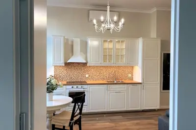 a kitchen with white cabinets and a table and a chandelier at Krakowska Street Old Town Apt 16 in Kraków