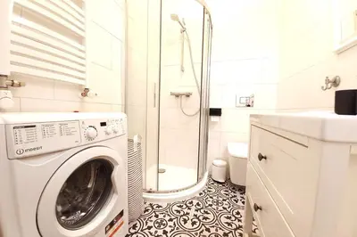 a washing machine in a bathroom with a shower at Krakowska Street Old Town Apt 16a in Kraków