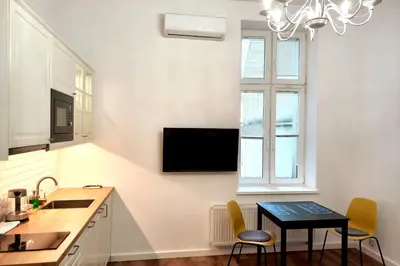 a kitchen with a small table and a tv on the wall at Krakowska Street Old Town Apt 16a in Kraków