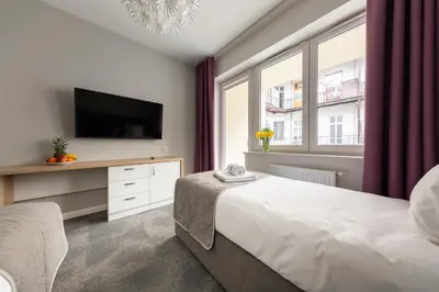 a bedroom with a bed and a tv and a window at PlayRoom Aparthotel in Kraków