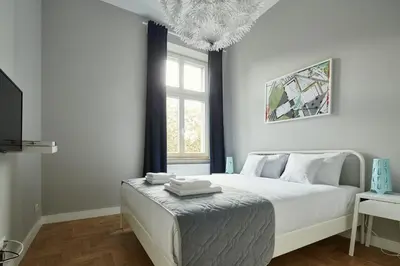 a white bedroom with a bed and a window at PlayRoom Aparthotel in Kraków