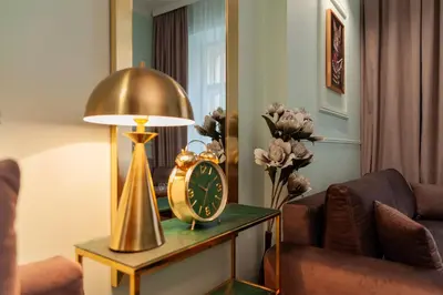 a room with a table with a clock and a lamp at Apartament Aria in Kraków