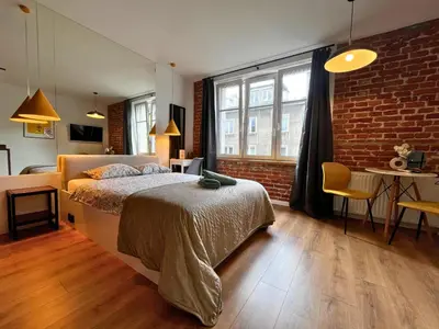 a bedroom with a bed and a brick wall at Jacuzzi Kraków Loft - Design Apartments in Kraków