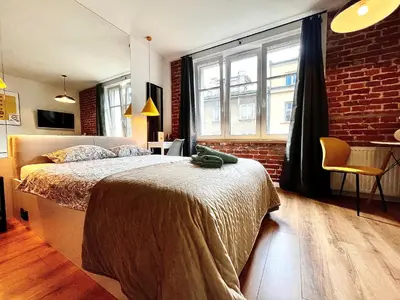 a bedroom with a bed and a brick wall at Jacuzzi Kraków Loft - Design Apartments in Kraków