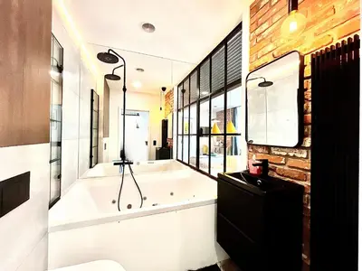 a bathroom with a bath tub and a sink at Jacuzzi Kraków Loft - Design Apartments in Kraków