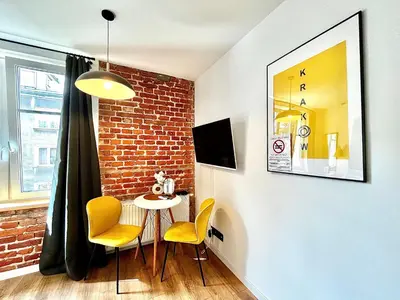 a dining room with a brick wall and a table and chairs at Jacuzzi Kraków Loft - Design Apartments in Kraków