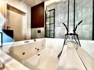 a bathroom with a large white bath tub at Jacuzzi Kraków Loft - Design Apartments in Kraków