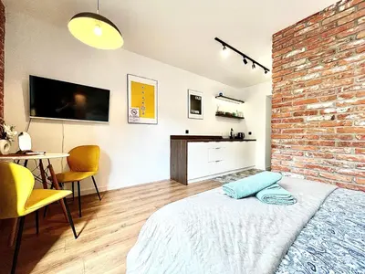 a bedroom with a brick wall and a bed and a table at Jacuzzi Kraków Loft - Design Apartments in Kraków