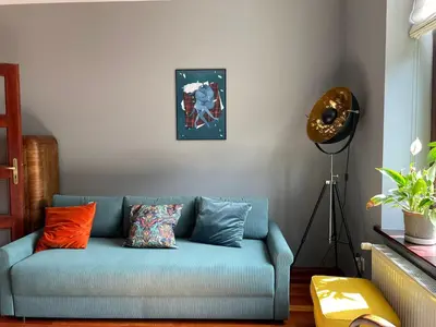 a blue couch in a living room with a clock on the wall at Dodo Acomodo 9 in Kraków