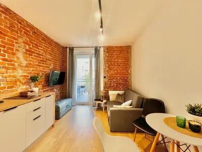 a kitchen and living room with a brick wall at Urban Loft with Terrace - Design Apartaments in Kraków