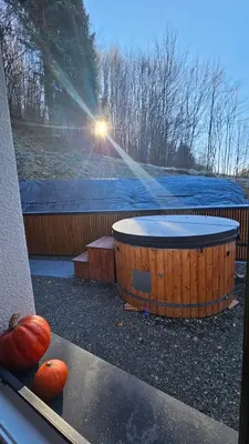a hot tub and pumpkins on a patio with the sun shining at Chata Pod Skarpą in Wieprzec
