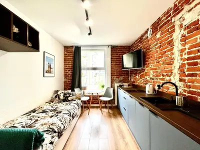 a kitchen with a couch and a brick wall at Cozy Loft - Design Apartaments in Kraków