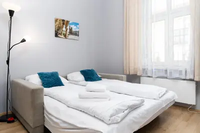 a white bed with blue pillows in a room at Cracow Old Town Apartment by BookingHost in Kraków