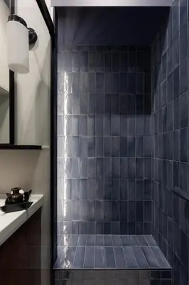 a bathroom with a shower with blue tiles at Noble Apartment in Kraków