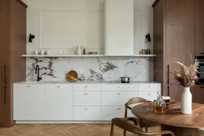 a kitchen with white cabinets and a wooden table at Noble Apartment in Kraków