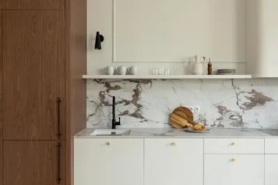 a white kitchen with a marble counter top at Noble Apartment in Kraków