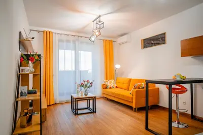 a living room with a yellow couch and a table at Krakow Studio Air Con 10th Floor Balcony in Kraków