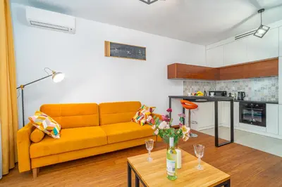 a living room with a yellow couch and a table at Krakow Studio Air Con 10th Floor Balcony in Kraków
