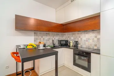 a kitchen with white cabinets and a black counter top at Krakow Studio Air Con 10th Floor Balcony in Kraków