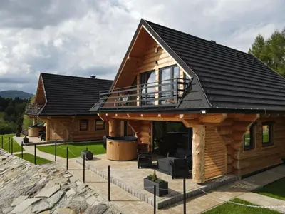 a log cabin with a porch and a deck at Domki Osada Klenina SAUNA & BALIA in Kamienica