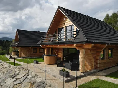 a log cabin with a black roof at Domki Osada Klenina SAUNA & BALIA in Kamienica