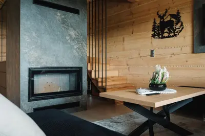 a living room with a table and a fireplace at Domki Osada Klenina SAUNA & BALIA in Kamienica