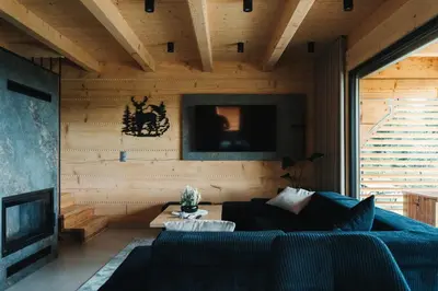 a living room with a blue couch and a tv at Domki Osada Klenina SAUNA & BALIA in Kamienica