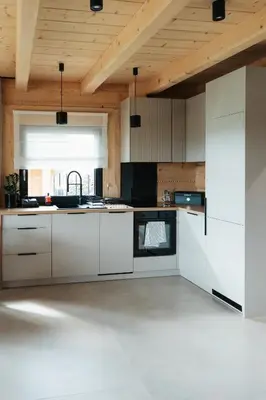 a kitchen with white cabinets and a wooden ceiling at Domki Osada Klenina SAUNA & BALIA in Kamienica