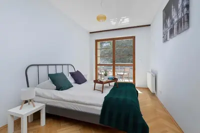 a white bedroom with a bed and a window at Kazimierza Wielkiego 2-Bedroom Apartment with Parking by Noclegi Renters in Kraków