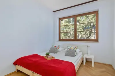 a bedroom with a bed with a red blanket and a window at Kazimierza Wielkiego 2-Bedroom Apartment with Parking by Noclegi Renters in Kraków