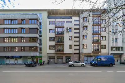a tall building with cars parked in front of it at Kazimierza Wielkiego 2-Bedroom Apartment with Parking by Noclegi Renters in Kraków