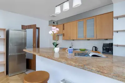 a kitchen with a granite counter top and a stainless steel refrigerator at Kazimierza Wielkiego 2-Bedroom Apartment with Parking by Noclegi Renters in Kraków