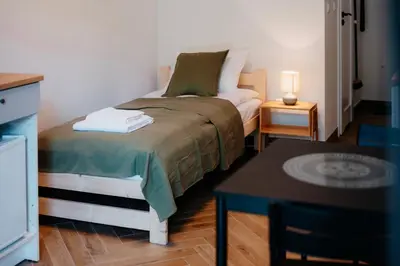 a small bedroom with a bed and a table at Airport Lux Balice in Szczyglice