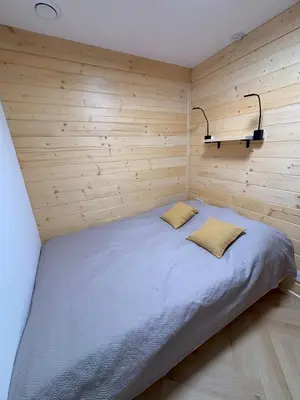a bed in a room with a wooden wall at Apartament pod lasem 2 - przy szlaku na Turbacz, w pobliżu wyciągów narciarskich in Nowy Targ