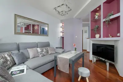 a living room with a couch and a tv at Grey and Pink Two Bedroom Apartment in Cracow with Parking, Desk, Terrace and Jacuzzi Bathtub by Noclegi Renters in Kraków