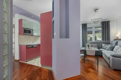 a kitchen and living room with a couch and a table at Grey and Pink Two Bedroom Apartment in Cracow with Parking, Desk, Terrace and Jacuzzi Bathtub by Noclegi Renters in Kraków