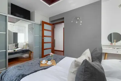 a bedroom with a bed with a tray on it at Grey and Pink Two Bedroom Apartment in Cracow with Parking, Desk, Terrace and Jacuzzi Bathtub by Noclegi Renters in Kraków