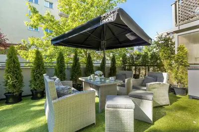 a patio with a table and chairs and an umbrella at Grey and Pink Two Bedroom Apartment in Cracow with Parking, Desk, Terrace and Jacuzzi Bathtub by Noclegi Renters in Kraków