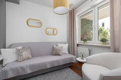 a living room with a couch and a window at Grey and Pink Two Bedroom Apartment in Cracow with Parking, Desk, Terrace and Jacuzzi Bathtub by Noclegi Renters in Kraków