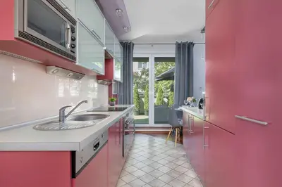 a kitchen with pink cabinets and a sink at Grey and Pink Two Bedroom Apartment in Cracow with Parking, Desk, Terrace and Jacuzzi Bathtub by Noclegi Renters in Kraków