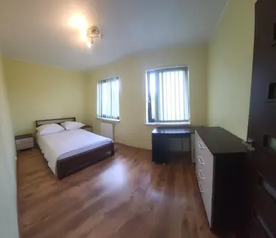 a bedroom with a bed and a desk and two windows at Apartament Lea in Kraków